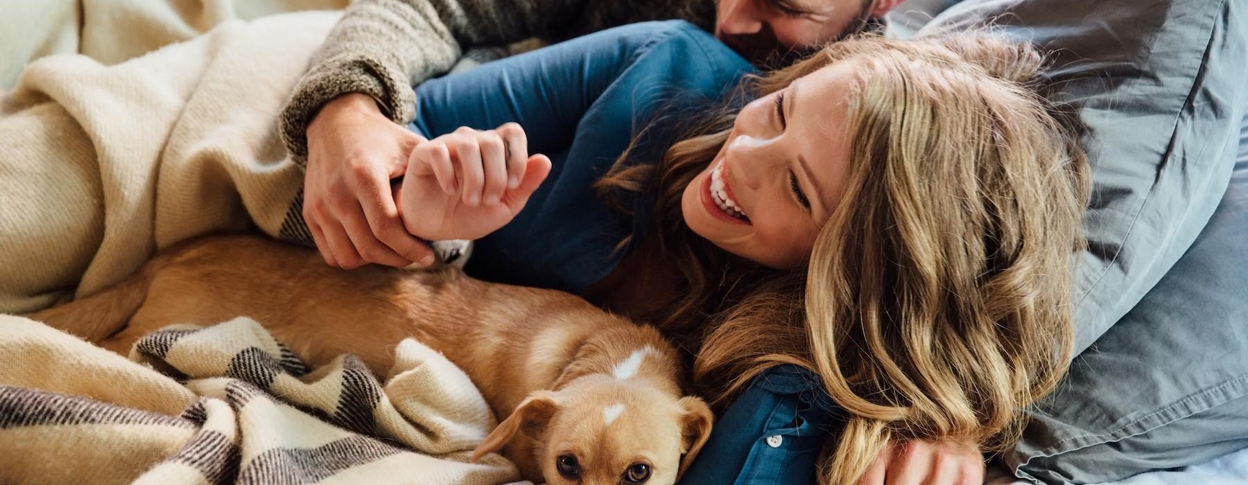 a man and woman lying in bed with a dog